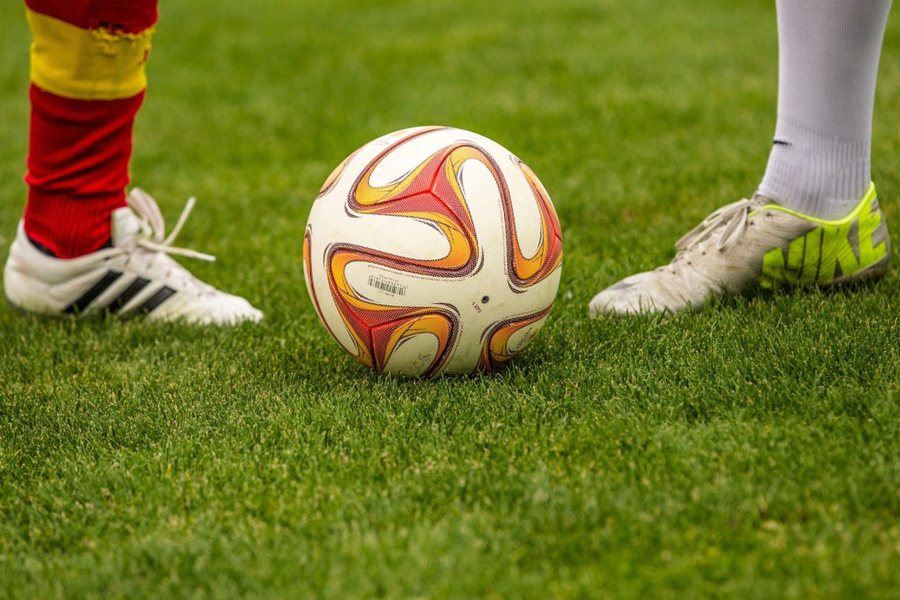 Twee jongeren met een voetbal op het gras